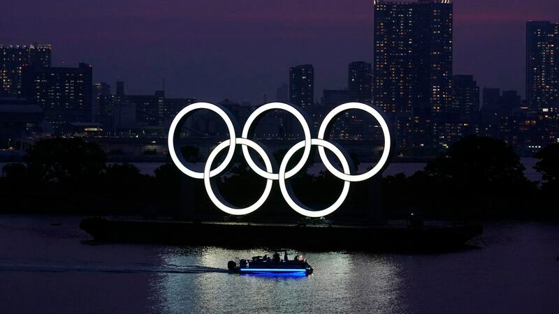 In this June 3, 2020, photo, the Olympic rings float in the water at sunset in the Odaiba...