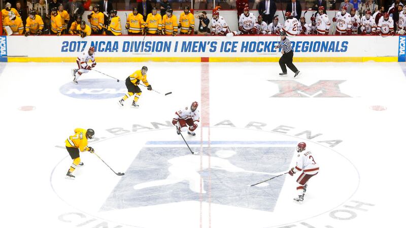 Michigan Tech's Reid Sturos (7) skates the puck up the ice against Denver's Emil Romig (18)...