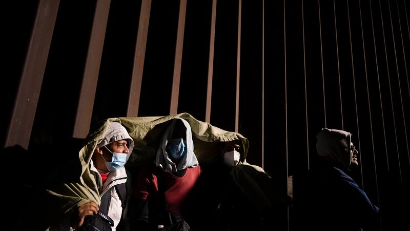 FILE - Four men from Cuba try to keep warm after crossing the border from Mexico and...
